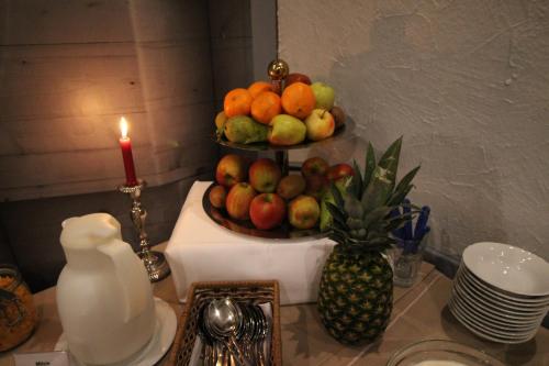 a plate of fruit on a counter with a candle and a pineapple at Hotel Restaurant Jägerhof in Braunschweig