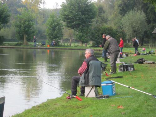 a man sitting on a chair fishing in a lake at Hotel De Watermolen in Bocholt