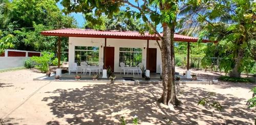 a house with a pavilion with white chairs and a tree at Surf Side Komari in Arugam Bay