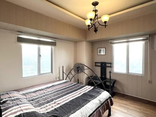 セブシティにある2-BR condo unit in IT Parkのベッドルーム1室(シャンデリア付きのベッド1台、窓2つ付)