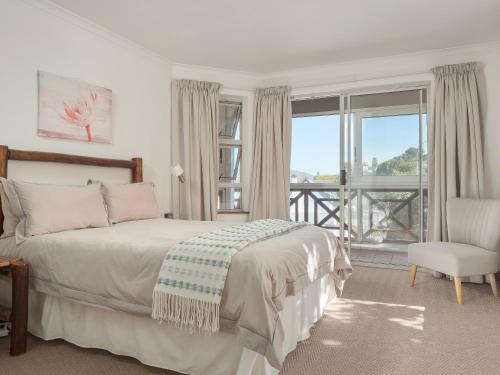 a bedroom with a bed and a chair and a window at Summer Place in Knysna