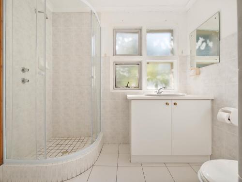 a white bathroom with a shower and a sink at Summer Place in Knysna