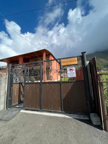 a gate to a house with a building behind it at Wander Kazbegi Hotel in Stepantsminda