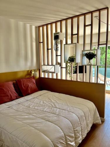 - une chambre avec un lit et un miroir au-dessus dans l'établissement Studio calme avec vue sur un grand Pin parasol, à Cannes