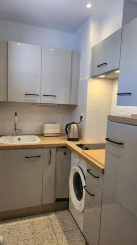- une cuisine blanche avec un lave-linge et un évier dans l'établissement Studio calme avec vue sur un grand Pin parasol, à Cannes