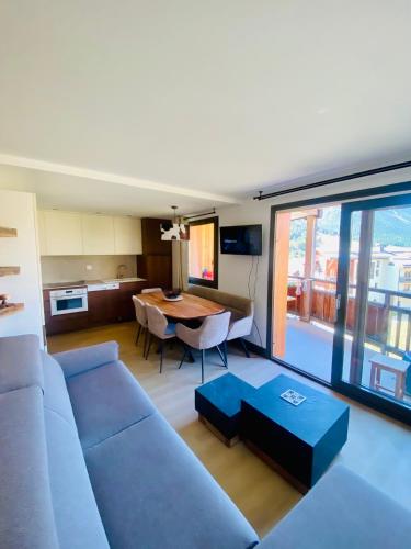 un salon avec un canapé bleu et une table dans l'établissement Le Cocon des Airelles - Meublé de tourisme 3 étoiles au pied des pistes avec garage, à Montgenèvre