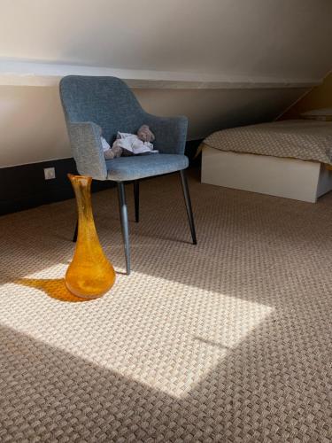 un ours en peluche farci assis sur une chaise dans une chambre dans l'établissement Le gîte du Cèdre, maison proche du Parc Astérix, à Éve