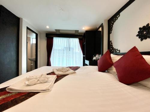 a bedroom with a large white bed with red pillows at Sunray Beach Hotel Patong in Patong Beach