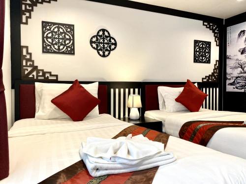 a hotel room with two beds with red pillows at Sunray Beach Hotel Patong in Patong Beach