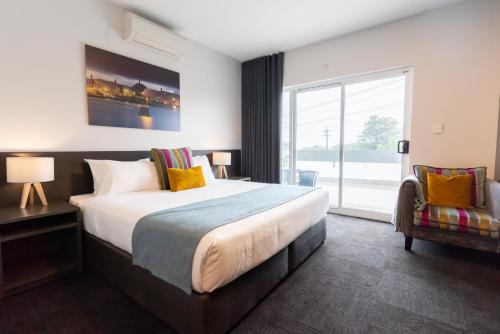a bedroom with a large bed and a large window at Coniston Hotel Wollongong in Wollongong