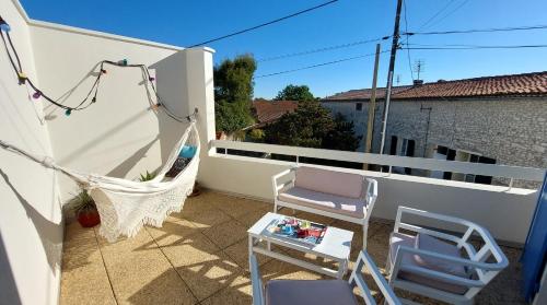 a patio with a hammock and chairs on a balcony at Maison au coeur de Meschers - proche des plages in Meschers-sur-Gironde