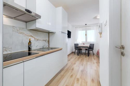 a kitchen with white cabinets and a table with chairs at Skyline Apartment in Veruda
