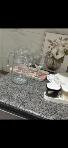a table with glasses and a vase on a counter at Lovely 2 Bedroom Furnished Apartments in Multan