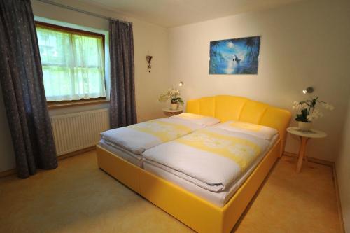 a yellow bed in a room with a window at Haus Hans-Jörg in Kelchsau