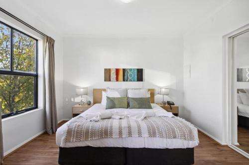 a white bedroom with a large bed and a window at Perth Prime Located 2BDR 1PRK in Perth