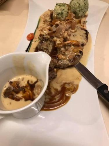a plate of food with meat and a bowl of dipping sauce at Hotel Häußler in Langenbruck