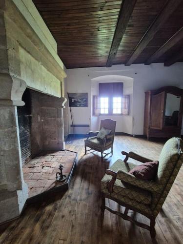 a living room with a stone fireplace and two chairs at Chateau de Presque in Saint-Médard-de-Presque