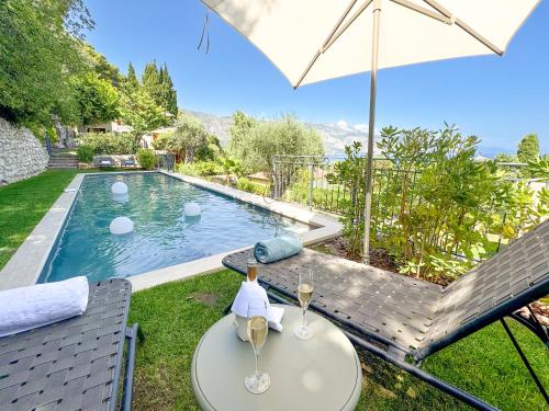 - une table avec des verres à vin et un parasol à côté de la piscine dans l'établissement Villa Aurora, à Saint-Jean-Cap-Ferrat