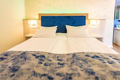 a large bed in a room with two lamps at Waldhotel Ehrental in Schmalkalden