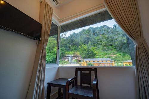 a room with a large window with two chairs and a table at Ethnic House Jr in Dồng Văn