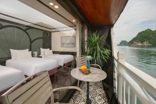 a room with two beds and a table on a boat at Hermes Cruises in Ha Long