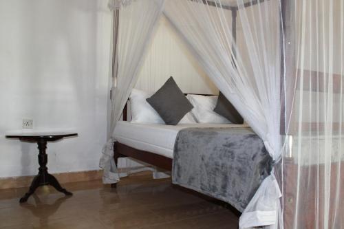 a bedroom with a canopy bed with a table at Sun and Surf Rest in Ahangama