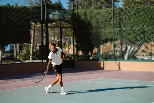 a man holding a tennis racket on a tennis court at Akassia Swiss Resort in Quseir