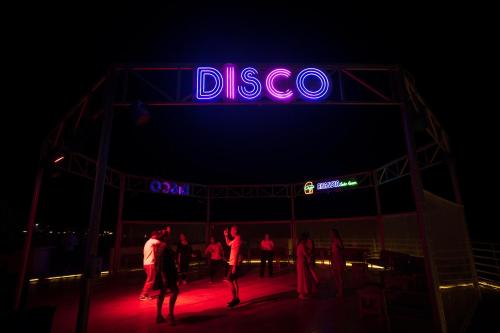 a group of people standing under a neon sign at night at Akassia Swiss Resort in Quseir
