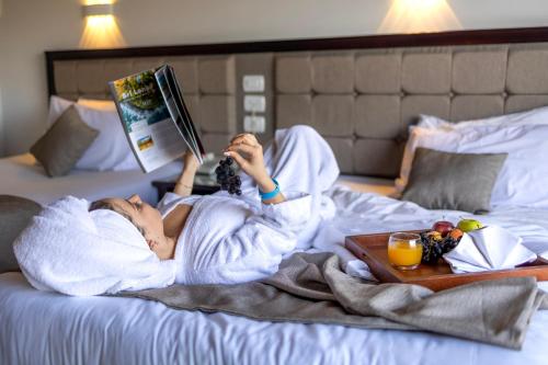 a woman laying on a bed reading a book at Akassia Swiss Resort in Quseir