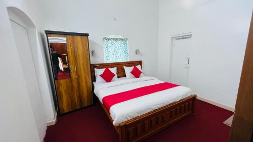 a bedroom with a large bed with red and white sheets at Hidden doors apartment in Ooty