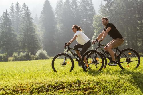 a man and woman riding bikes in a field at Posthotel Achenkirch Resort and Spa - Adults Only in Achenkirch