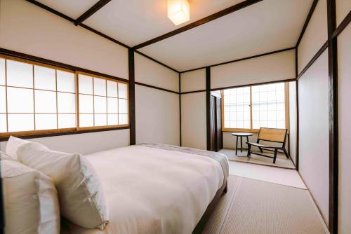 a bedroom with a bed and a table and windows at SKI INN HAKUBA in Otari