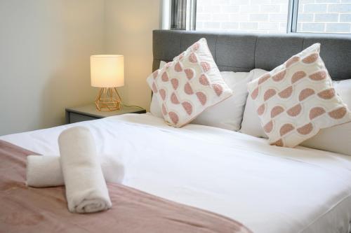 a bedroom with a white bed with pillows and a lamp at Denham Court 4Br with Central AC & WiFi near Coles in Leppington