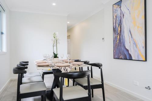 a dining room with a table with chairs and a painting at Denham Court 4Br with Central AC & WiFi near Coles in Leppington