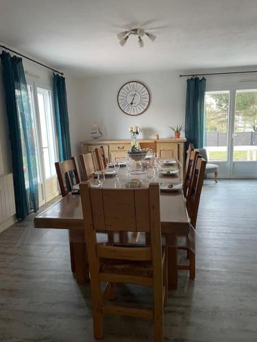 une table à manger avec des chaises et une horloge murale dans l'établissement Pavillon bord de mer - 10min des plages en vélo, à Le Fenouiller
