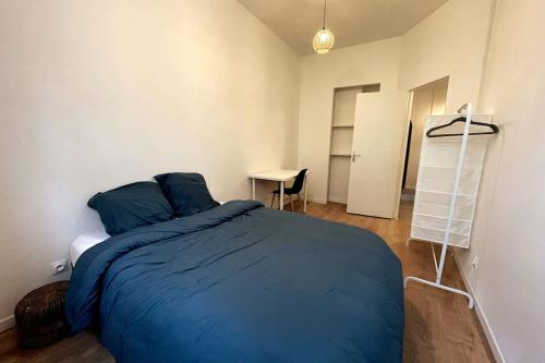 Schlafzimmer mit einem blauen Bett und einem Schreibtisch in der Unterkunft Le Grand Loft in Saint-Étienne