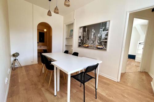 ein Esszimmer mit einem weißen Tisch und Stühlen in der Unterkunft Le Grand Loft in Saint-Étienne