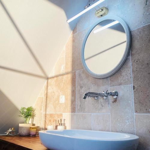 a bathroom with a round mirror and a tub at Greenhell Farmhouse in Nohn