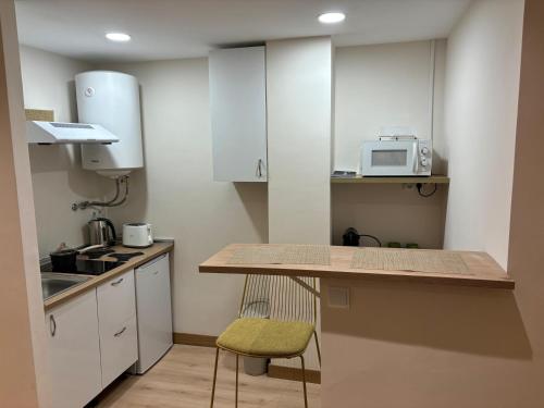 a small kitchen with white cabinets and a green chair at Las Estrellas de Soria in Soria
