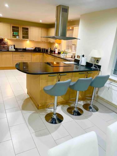 a kitchen with a counter and two bar stools at Luxurious Executive 5 Bedroom Whole Home - For 10 in Hensol