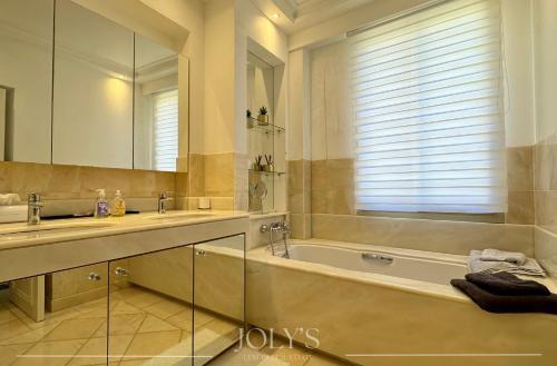 une salle de bain avec une baignoire, un lavabo et un miroir dans l'établissement Appartement lumineux de 120m2 - Palm Beach, à Cannes