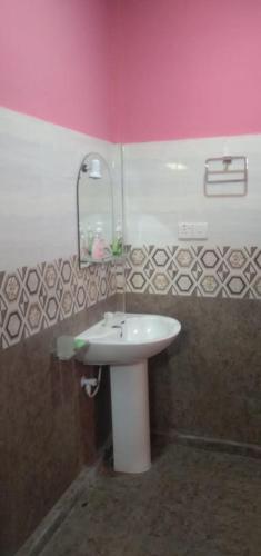 a bathroom with a white sink and a pink wall at Trinco White Villa in Trincomalee