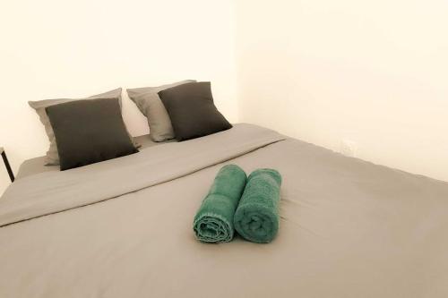 - un lit blanc avec 2 serviettes vertes dans l'établissement Le Wagner Proche Gare, à Nancy