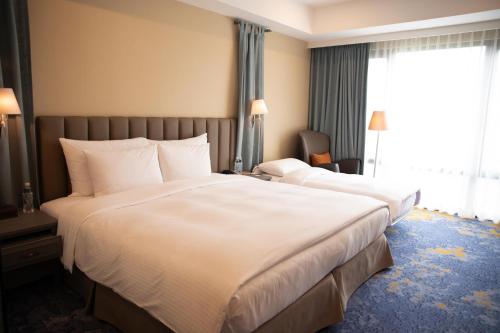 a hotel room with two beds and a window at Grand Victoria Hotel in Taipei