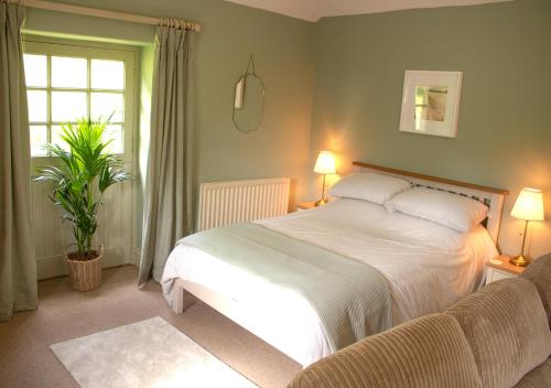 a bedroom with a white bed and a window at The Old Barn at Bosillion House in Grampound
