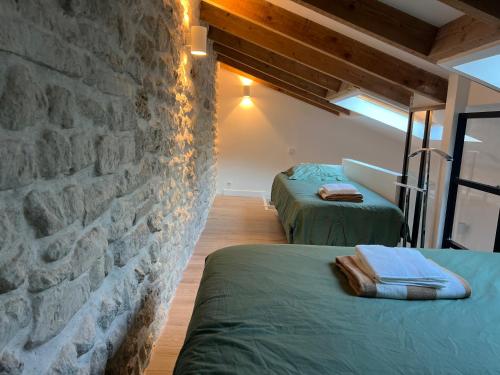 Cette chambre comprend 2 lits et un mur en pierre. dans l'établissement Duplex plein Sud, à Paris