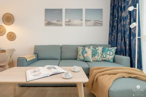 ein Wohnzimmer mit einem Sofa und einem Tisch mit einem Buch in der Unterkunft Polanki Aqua Exclusive - by Jantar Apartamenty Kołobrzeg in Kołobrzeg