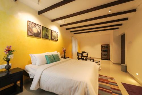 a bedroom with a large white bed and yellow walls at Akkandi Veedu in Kodaikānāl