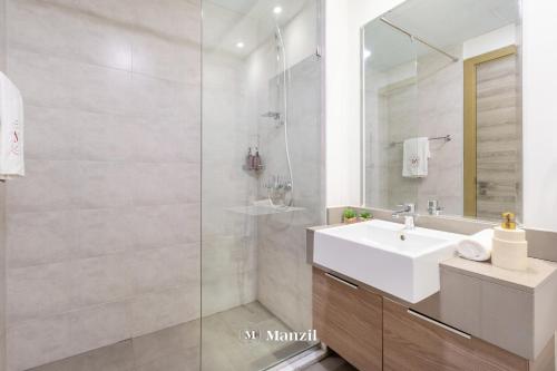 a white bathroom with a sink and a shower at Manzil - Stylish living in JVC, City Views and Pool in Dubai