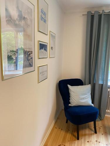 a blue chair in a room with pictures on the wall at FoRest House in Rosenfors